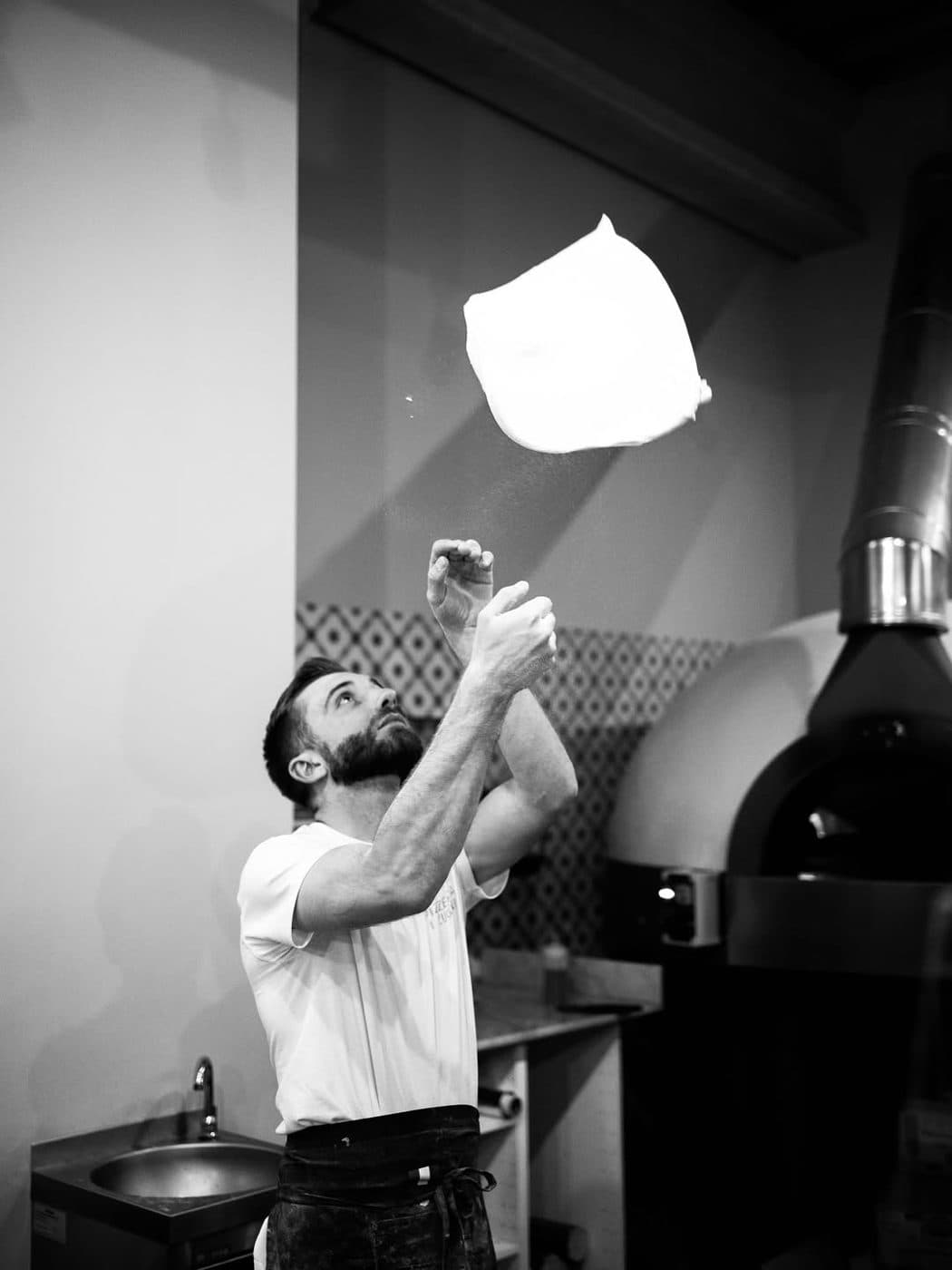 Pizzaiolo lançant la pâte en l'air, noir et blanc